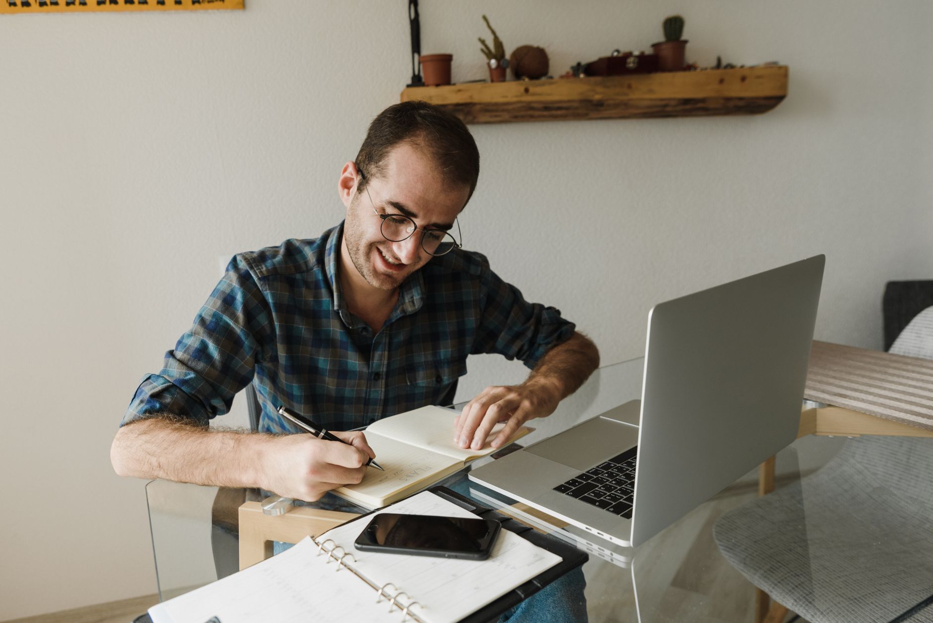 Adulto iniciante estudando inglês em casa com caderno e laptop, sorrindo