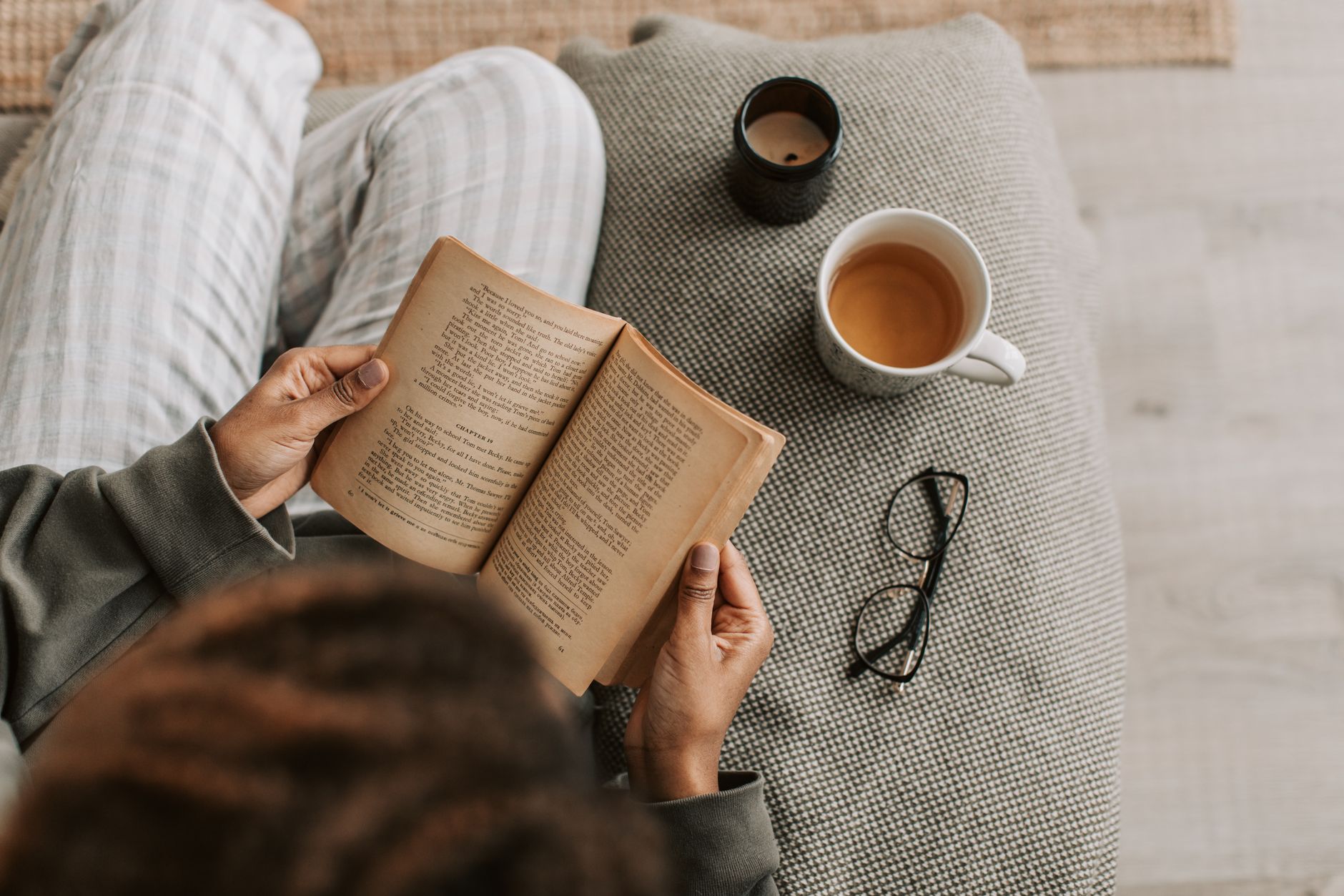 Pessoa lendo um livro em inglês com uma xícara de chá ao lado